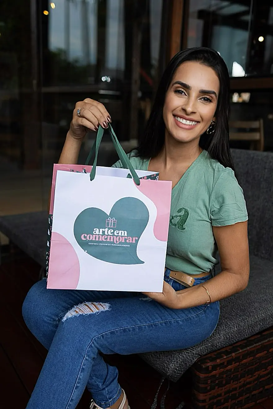 Fundadora da Arte em Comemorar sorrindo e segurando a sacola da marca